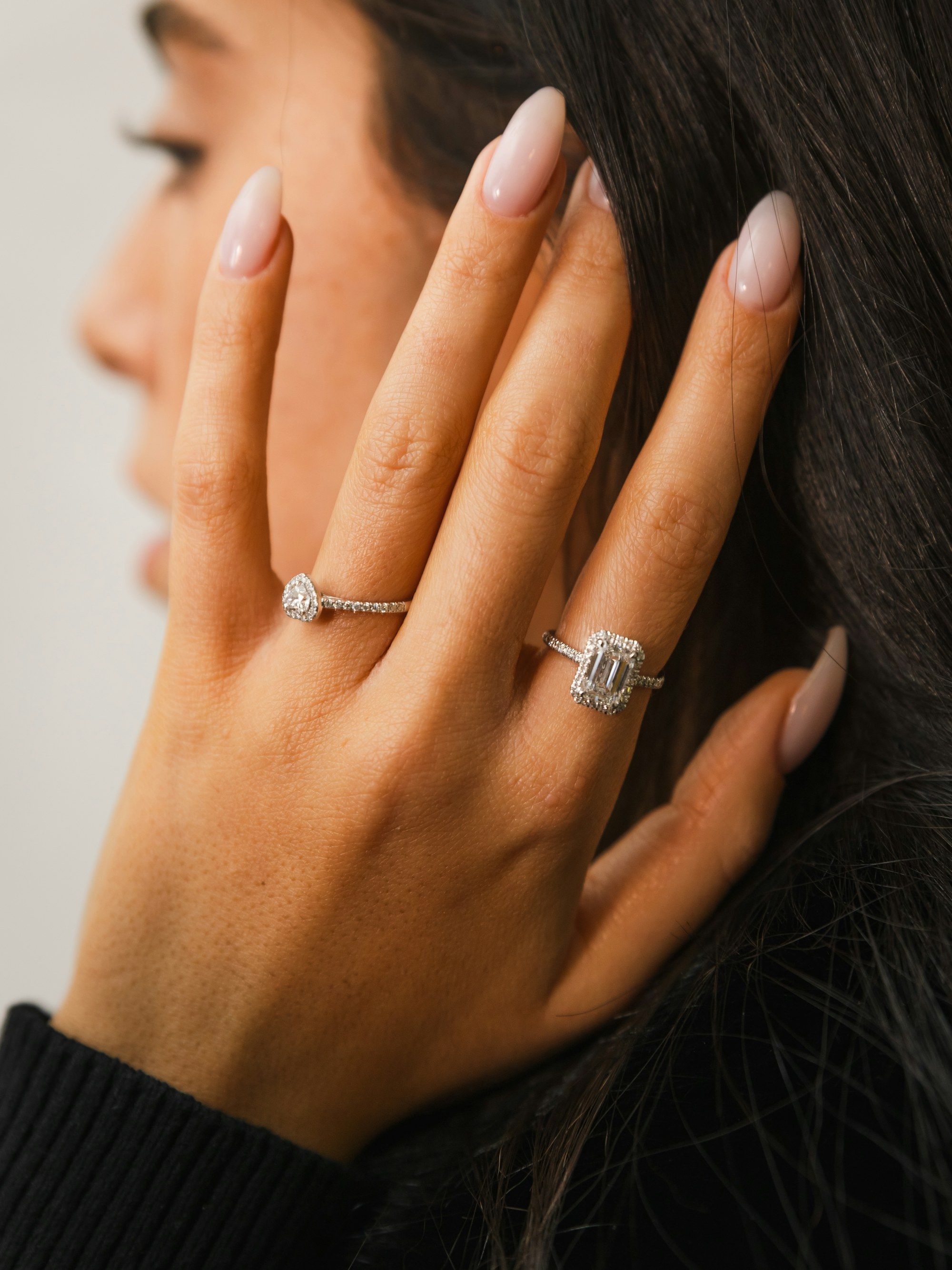 Hand touching the face, wearing a diamond ring and a band